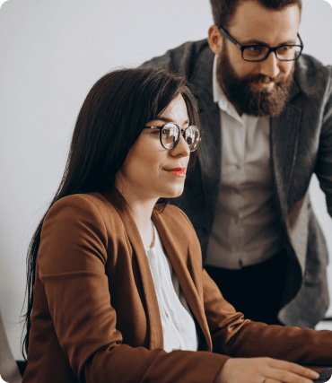 Mulher e colega de trabalho no escritório de frente para uma tela.